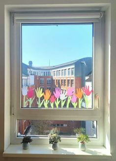 the window is decorated with paper flowers and potted plants