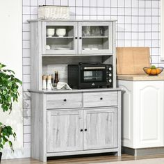 a kitchen area with a microwave, counter top and cabinets in white tile wallpaper