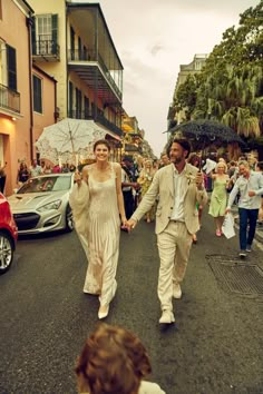 a man and woman walking down the street in front of some people with umbrellas