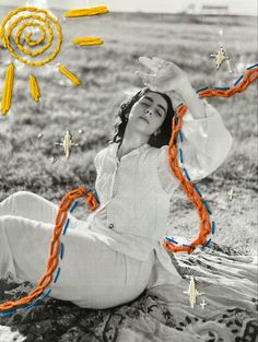 a woman sitting on the ground with her hands up in the air while holding an orange string