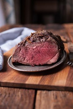 a piece of meat sitting on top of a wooden table next to a knife and fork