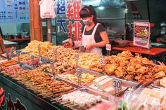 a woman standing in front of a counter filled with food