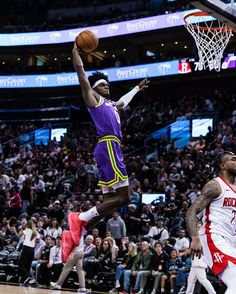 a basketball player jumping up to dunk the ball in front of an arena full of people