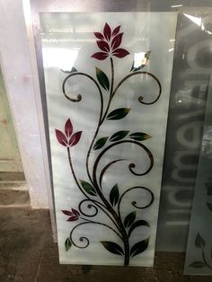 a decorative glass panel with flowers and leaves painted on the side of it, in front of a window