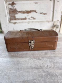 an old brown suitcase sitting on top of a wooden floor