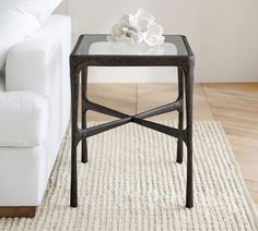 a white couch sitting next to a glass table on top of a rug in a living room