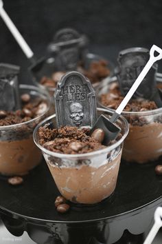 three dessert cups with chocolate pudding and tombstones in them