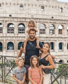 a family poses for a photo in front of the colossion, with one child on his shoulders