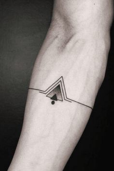 a black and white photo of a person's arm with a triangle tattoo on it