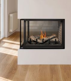 a fireplace with wood burning inside of it on a hard wood floor next to a white wall