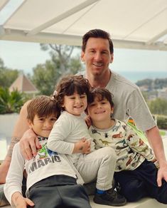 a man sitting on top of a white bench with two small children in front of him