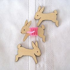 two wooden reindeer ornaments on a white table cloth with pink ribbon and bow in the middle