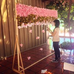 a woman standing in front of a pink flower display