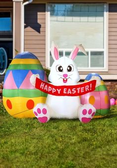 an inflatable bunny holding a happy easter sign on the front lawn of a house