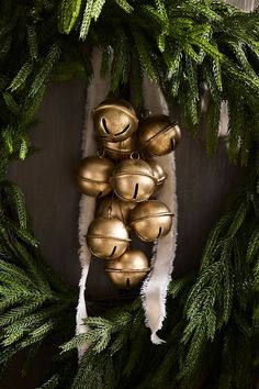 a bunch of bells hanging from the side of a christmas tree with green leaves on it