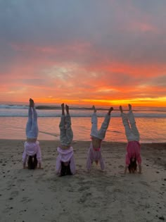 three girls doing handstands on the beach at sunset