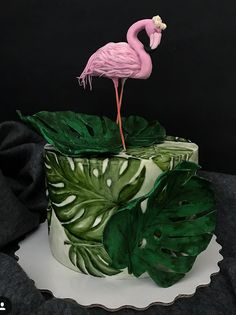 a pink flamingo sitting on top of a green leaf covered cake