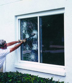 a man is holding a window pane and looking at the shattered glass in front of him