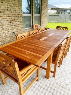 a wooden table and chairs on a patio with grass in the back ground behind it