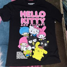 Black And Pink Hello Kitty And Friends T-Shirt Kawaii Black T-shirt With Letter Print, Kawaii Black Top With Character Print, Black Kawaii Top With Character Print, Black Kawaii T-shirt With Funny Print, Black Kawaii T-shirt With Character Print, Kawaii Black Crew Neck T-shirt, Black Kawaii T-shirt With Hello Kitty Print, Trendy Pink Hello Kitty T-shirt, Pink Hello Kitty Graphic Tee