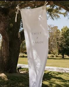 a white banner hanging from a tree in the grass with an inscription that reads, family and aaron on it