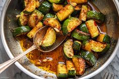 a pan filled with cooked zucchini on top of a table next to a wooden spoon