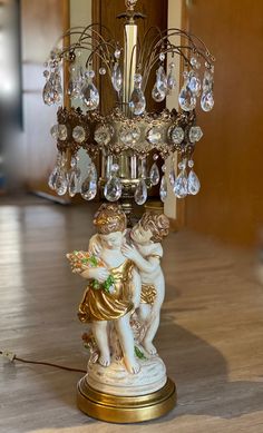 an antique chandelier with two cherubs and crystal drops hanging from it