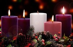 three lit candles with christmas decorations around them