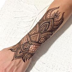 a woman's arm with an intricate tattoo design on her left forearm and foot