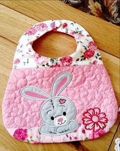 a pink bib with an image of a bunny on the front and flowers on the back