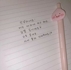 a pink pen with writing on it sitting next to a piece of lined paper