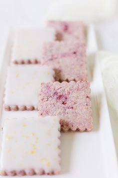 four different types of cookies on a white plate with pink and yellow sprinkles