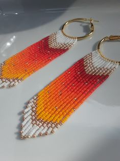 two pairs of beaded earrings with gold hoops and orange, yellow and white beads