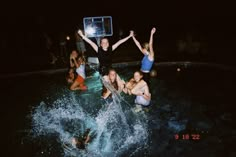 several people in the water with their arms up and one person holding a basketball hoop