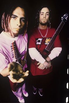 two young men with dreadlocks are posing for a photo while holding their guitars