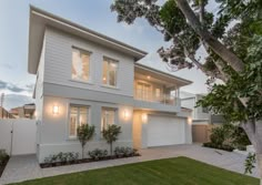 a white two story house with lots of windows on the front and side of it