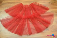 a red tulle skirt is on the floor in front of a wood flooring