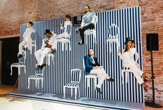 a group of people sitting on top of chairs in front of a large wall mural