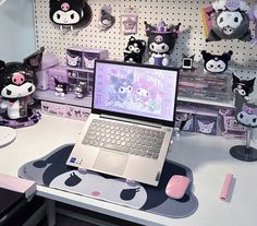 an open laptop computer sitting on top of a desk next to stuffed animals and toys