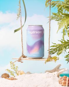 a can of beer on a swing with sea shells and palm trees in the background