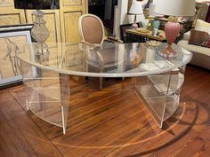 a clear glass table in a living room with wooden flooring and furniture around it