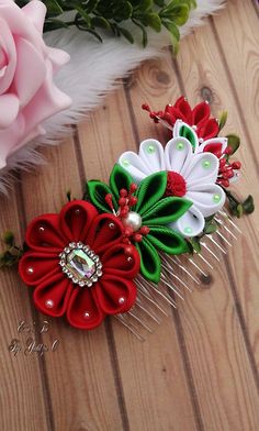 two hair combs with flowers on them sitting next to pink roses and green leaves