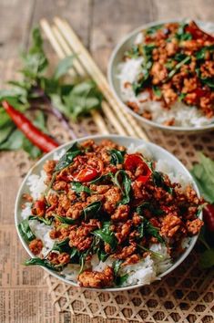 two white bowls filled with meat and vegetables on top of rice next to chopsticks