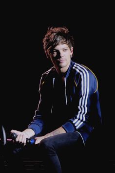 a young man sitting on top of a chair holding a remote control in his hand