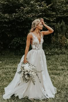 a woman in a wedding dress holding a bouquet and posing for the camera with her hand on her head