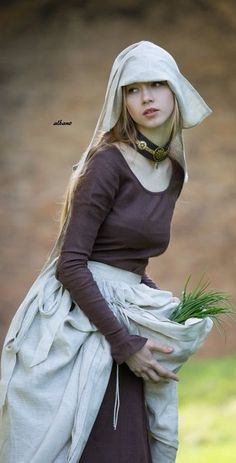 a woman dressed in medieval clothing holding grass