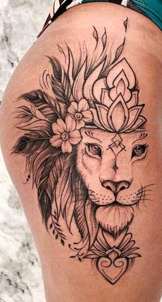 a woman's thigh with a lion tattoo on it and flowers in her hair