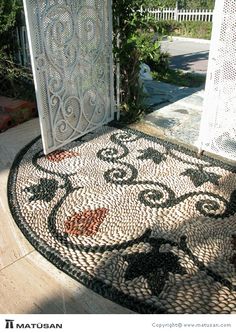 an outdoor area with a mosaic design on the ground and a gate in the background