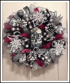 a christmas wreath with snowflakes and other decorations hanging on a door hanger