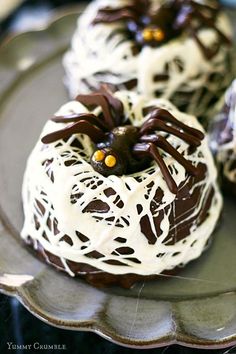 chocolate covered desserts with white frosting and spider decorations on a silver platter